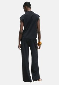 Black two-piece outfit featuring a short-sleeve top and wide-leg pants. The fabric has a smooth texture, and the design is minimalist.