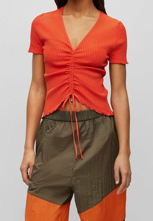 Rotes, geripptes Kurzarm-Oberteil mit tiefem V-Ausschnitt und gerafftem Frontdetail, ausgestattet mit einem verstellbaren Kordelzug am Saum und einer cropped Silhouette.