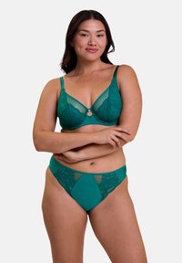 Soutien-gorge en dentelle et en tulle teal avec armatures et bretelles réglables, présentant un détail décoratif au centre. Culottes assorties teal avec des accents en dentelle.