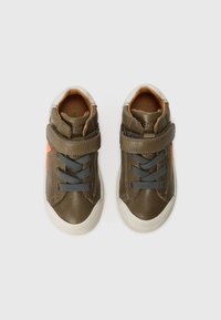 Brune lær-sneakers med grå snørebånd og borrelåsrem, med oransje detaljer, rund tå og teksturert gummisåle.