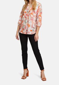 Kevyet, kuviolliset puserot vaaleanpunaisena, oranssina ja harmaana, joissa on 3/4-hihat, yhdistettynä kapeisiin mustiin housuihin ja oransseihin lohko-korkokenkiin.