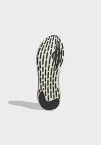 Adidas sneaker outsole with a white rubber base, featuring black traction grooves and a textured pattern, and branded logo detail.