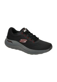 Scarpa sportiva nera con parte superiore in mesh, dettagli rossi, suola con spessa ammortizzazione e sistema di allacciatura. Presenta un logo prominente sul lato.