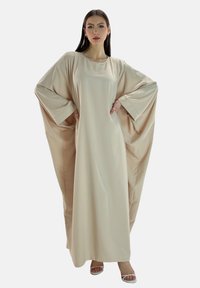 Abito lungo beige con maniche ampie, realizzato in tessuto morbido. Presenta un collo rotondo e una silhouette fluida.