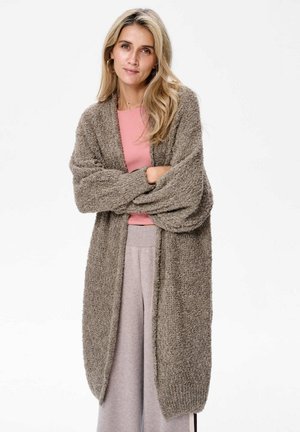 Lange, open voorkant cardigan van textuur bruin gebreid materiaal, met brede mouwen en een ontspannen pasvorm, gelaagd over een lichtroze top en grijze broek.