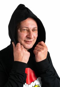 Felpa nera con cappuccio e maniche lunghe, con una grafica natalizia colorata. Il tessuto è liscio e il cappuccio è alzato. Mani che stringono il tessuto.