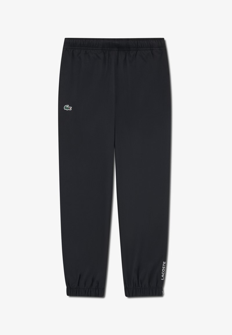 Pantalon de sport noir en tissu léger, avec une taille élastique, des chevilles resserrées et un petit logo Lacoste vert sur le côté.