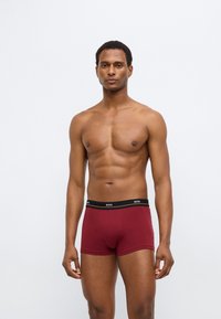 Rode boxershorts gemaakt van zachte stof, met een zwarte tailleband met het "BOSS"-logo. Een getailleerde pasvorm met een gladde textuur en strakke lijnen.