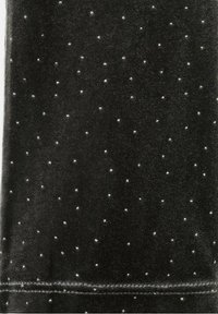 Tissu noir avec de petits points argentés régulièrement espacés et une couture horizontale visible près du bord inférieur.