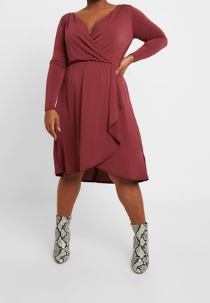 Vinrød omslagskjole med lange ærmer, dyb V-hals og drapering foran. Kombineret med ankelstøvler med slangeskindsmønster. Glat tekstur.