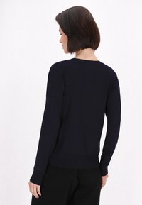 Maglione a maniche lunghe di colore blu navy, realizzato in un morbido tessuto a maglia. Presenta un orlo e polsini a coste, con un design a collo rotondo e una forma aderente.