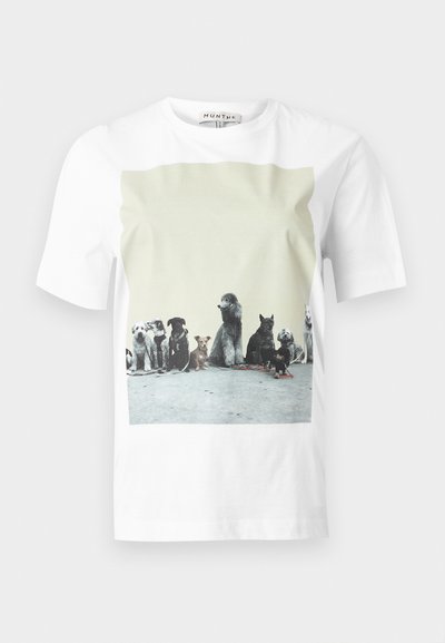 T-shirt blanc à manches courtes avec une photo imprimée de neuf races de chiens différentes assises sur un sol en béton contre un mur uni.