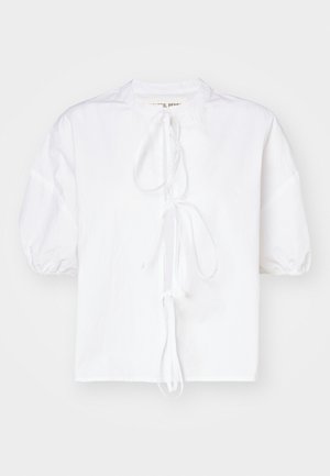 Weißes Blusenshirt mit Puffärmeln aus leichtem Stoff, das eine Bindeschnürung am Hals und einen leicht lockeren Schnitt für zusätzlichen Tragekomfort aufweist.