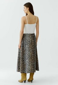 Weißes Cami-Top, kombiniert mit einem knöchellangen Rock im Leopardenmuster. Hat ein fließendes Design und gelb-braune High Heels.