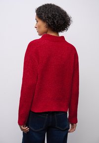 Rode gebreide trui met een hoge kraag, een drop shoulder ontwerp en geribde manchetten. Casual pasvorm, textuurstof en een cropped lengte aan de achterkant.