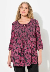 Florale Tunika mit schwarzem Hintergrund und pinkfarbenen Mustern, ausgestattet mit einem Rundhalsausschnitt, einem Schlüsselelement mit Bindeband und lockeren 3/4-Ärmeln.