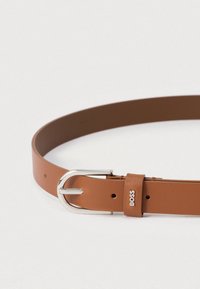 Καφέ δερμάτινη ζώνη με ασημένια μεταλλική αγκράφα και θηλιά με ανάγλυφο το λογότυπο "BOSS" σε ανοιχτό φόντο.