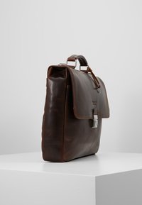 Brun læder aktetaske med flad design, metalbeslag, topgreb og magnetlukning. Glat tekstur med minimale detaljer.