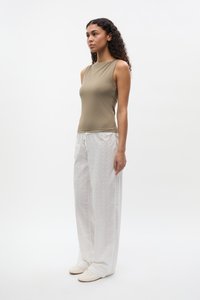 Khaki sleeveless top in stretchy fabric paired with white patterned wide-leg pants; pants feature a drawstring waistband and subtle texture.