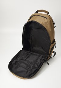 Bruine rugzak met een ruime zwarte binnenkant, voorzien van meerdere zakken en ritssluitingen. Duurzaam stoffen buitenkant, ergonomisch ontwerp.