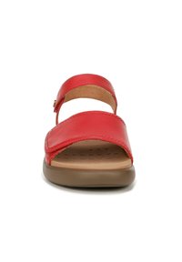 Red leather sandal with wide straps, an open toe, and adjustable buckle. Brown rubber sole features dot texture for grip and comfort.