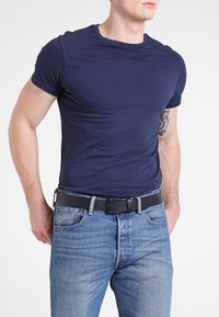 T-shirt ajusté bleu marine à manches courtes porté avec un jean bleu clair et une ceinture noire. Tissu lisse, col rond simple, design classique.