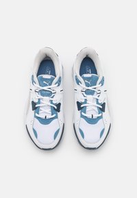 Zapatillas deportivas blancas con acentos azules, paneles de malla y lengua acolchada. Presentan un diseño de cordones y suela de goma para agarre.