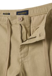 Pantalons en coton beige à coupe décontractée. Dotés d'une fermeture éclair, d'un bouton et d'une taille élastique. Détail en texure chevron sur le tissu.