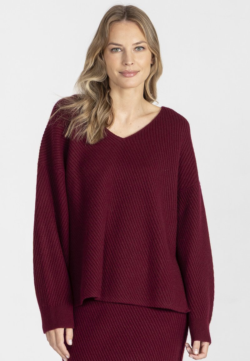 Bordowy sweter z prążkowanego materiału z dekoltem w serek, długimi rękawami i luźnym krojem. Miękka tekstura zwiększa ciepło i komfort. Zaprojektowany z myślą o codziennym noszeniu.