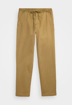 Light brown, elastic waist pants with drawstring, featuring two side pockets and a relaxed fit. Fabric appears smooth with a subtle sheen.
