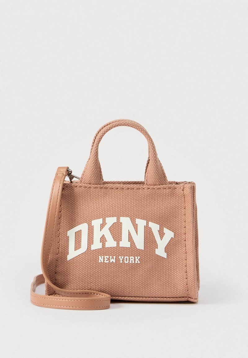 Geantă de mână din material roz texturat, cu două mânere superioare și curea detașabilă. Pe partea din față este evidențiat logo-ul alb "DKNY NEW YORK".