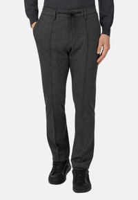 Grå, figursydd joggers i stickad tyg, med dragsko i midjan, sidfickor och kontrasterande sömmar för extra detalj.