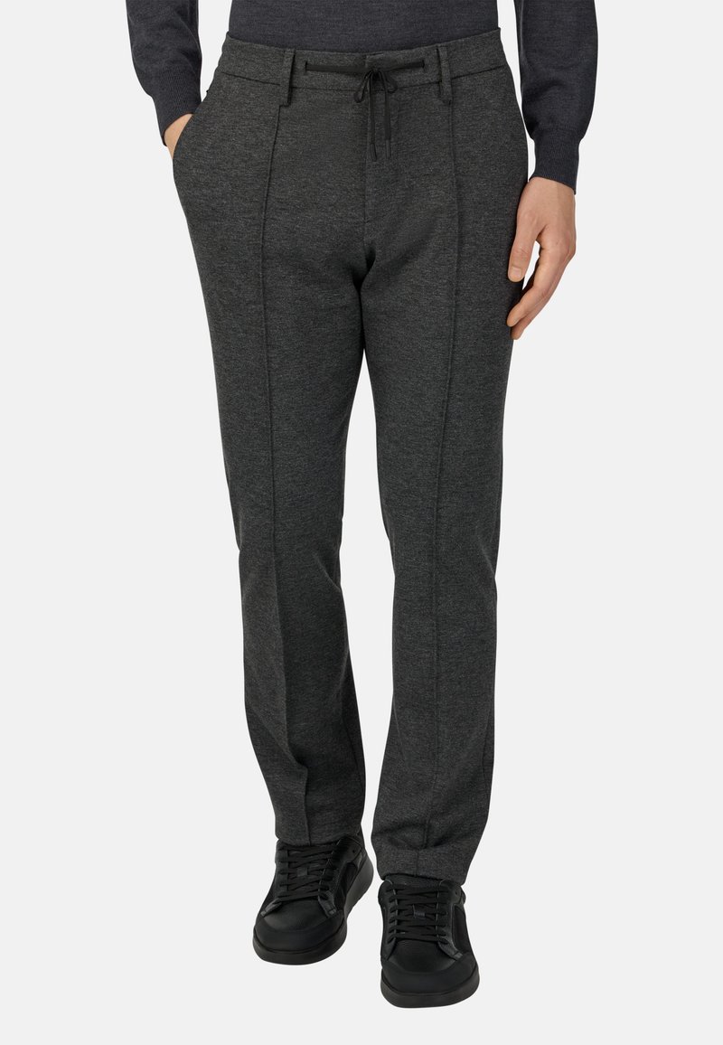 Grå, figursydd joggers i stickad tyg, med dragsko i midjan, sidfickor och kontrasterande sömmar för extra detalj.
