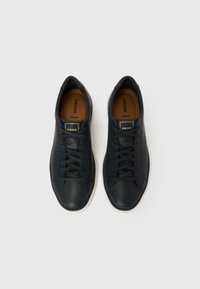 Ζευγάρι μαύρα δερμάτινα αθλητικά παπούτσια Geox με μαύρα κορδόνια και μπεζ εσωτερικές σόλες, τοποθετημένα δίπλα-δίπλα σε λευκό φόντο.