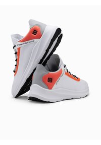 Scarpe atletiche bianche con tomaia in rete traspirante, dettagli arancioni, lacci neri e suola testurizzata per una migliore aderenza. Visibile il marchio "Ombre Footwear".