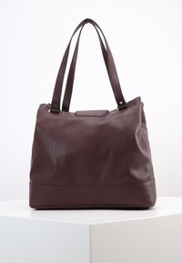 Maroon leather tote bag with smooth texture, dual straps, and a slightly structured shape. Accented by subtle stitching and a solid base.