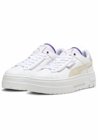 Sneaker bianche con suola piatta texturizzata, caratterizzate da un accento in suede beige e dettagli viola sulla linguetta e sul colletto.