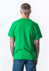 Grøn bomulds t-shirt med korte ærmer og rund halsudskæring, set fra bagfra, parret med blå denim jeans.