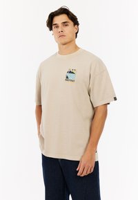 Beige katoenen T-shirt met een ronde hals, voorzien van een kleurrijke grafische print met het label "PROTEST" aan de linkerbovenkant.