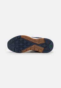 Námořnické modr�é sportovní boty s podrážkou z texturované gumy, s hnědým mezidílem a zeleným akcentem blízko paty. Viditelné logo Timberland.