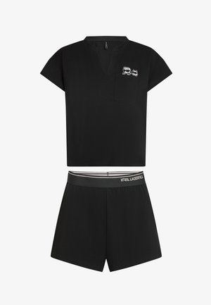 Črni dvodelni komplet, ki vključuje majico s kratkimi rokavi z žepom in grafičnim Detajlom ter kratke hlače z elastiko v pasu, izdelan iz mehke tkanine.