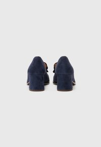 Navy blue suede heels with a block heel design, featuring a textured surface and smooth leather accents on the interior.