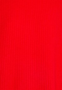 Tissu tricoté rouge avec texture côtelée verticale, lignes espacées uniformément et couleur vibrante.