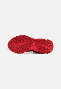 Rød gummisål til sneakers med detaljeret tekstur, der har et cirkulært design og branddetaljer, designet til greb og holdbarhed.