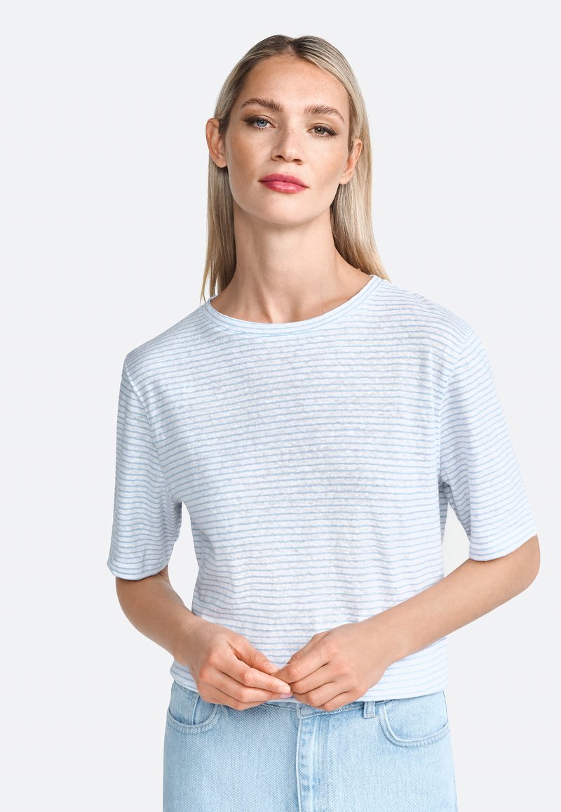T-shirt rayé bleu clair à manches courtes, col rond et texture douce, associé à un jean en denim bleu clair.
