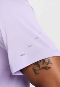 Lavender athletic shirt featuring short sleeves, smooth fabric texture, and three grey horizontal stripes on the sleeve near the shoulder.