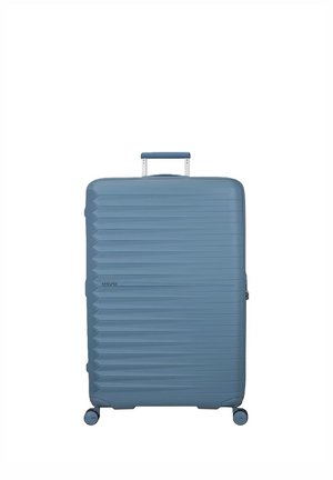 Großer blauer Hartschalenkoffer mit horizontalen Rillen, vier Rollen und einem ausgezogenen Griff, zentriert vor weißem Hintergrund.