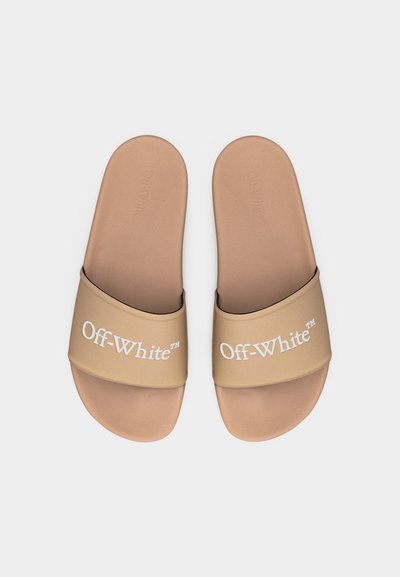 Ζευγάρι μπεζ σαγιονάρες Off-White με φαρδιές λουρίδες και ανάγλυφες σόλες σε ουδέτερο φόντο.