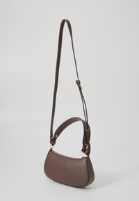 Brown leather shoulder bag with a curved shape, gold hardware accents, and an adjustable strap. Textured surface with zipper closure.