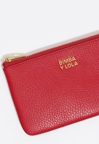 Raudona tekstūrinė odinė užtrauktuko kišenė su auksiniu logotipu "BIMBA Y LOLA" priekyje. Įrengta aukso spalvos užtrauktuku ir lygiomis kraštinėmis.
